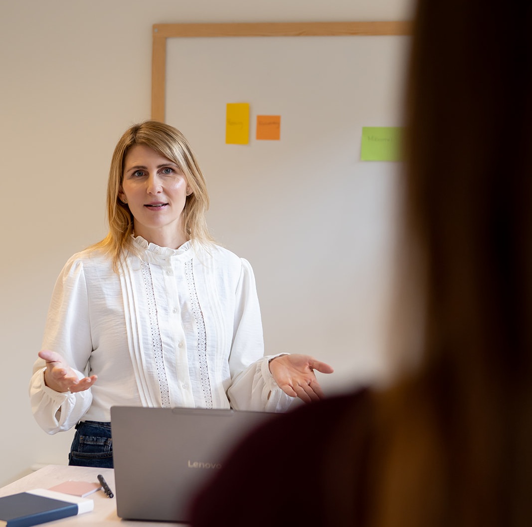 Marianne Holmgaard stående ved tavle i dialog med deltager på workshop